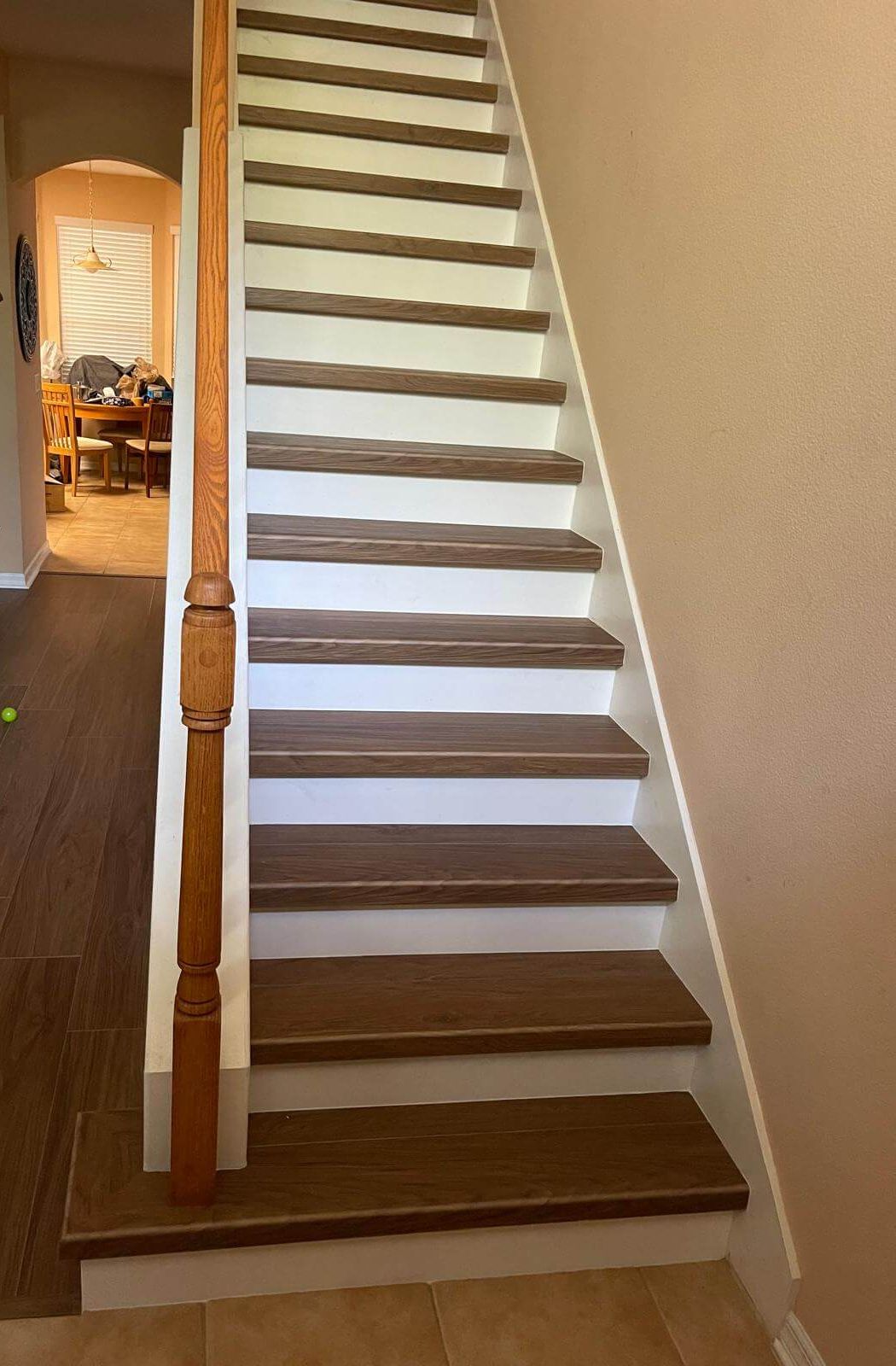 Straight staircase with wood-look vinyl treads, white risers and wood handrail